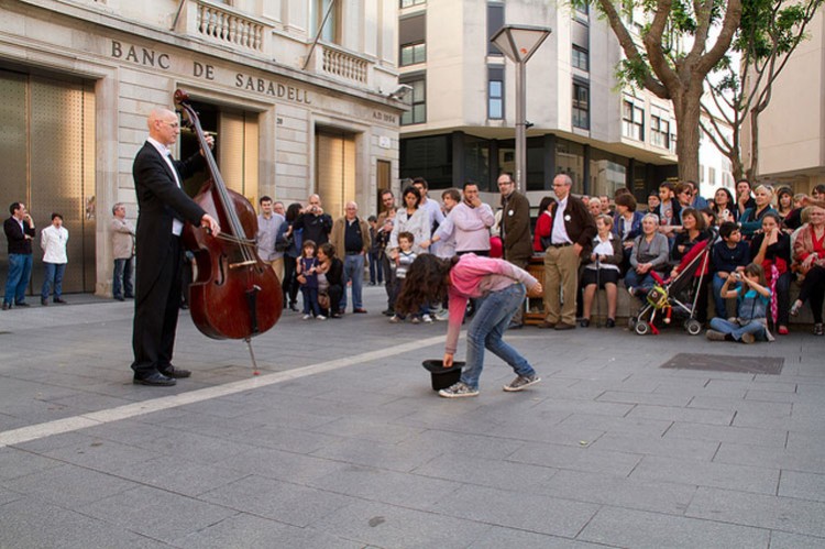 una niña da una moneda a un músico